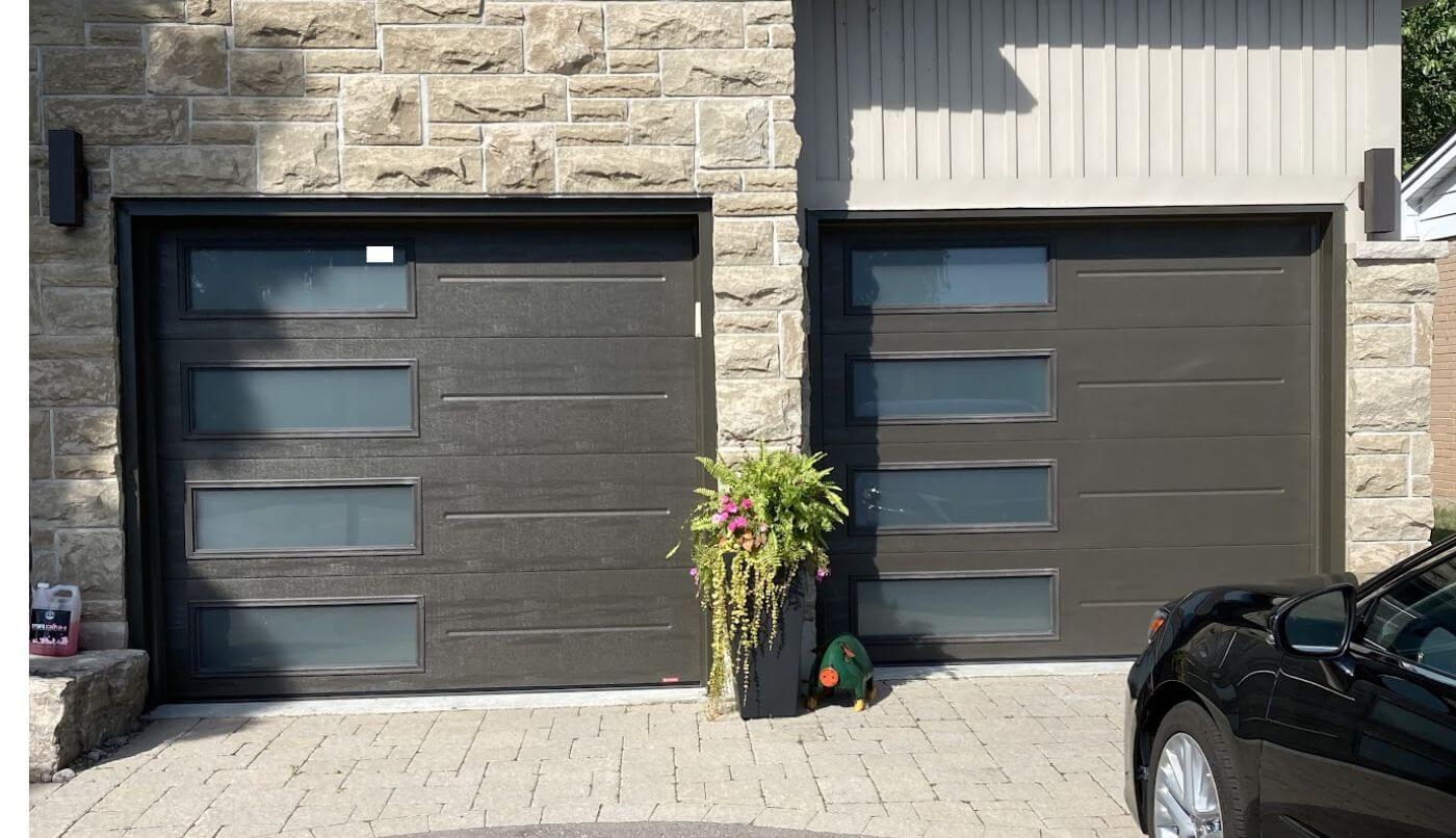 Two garage doors featuring glass windows, providing a modern aesthetic and natural light to the exterior of a home.