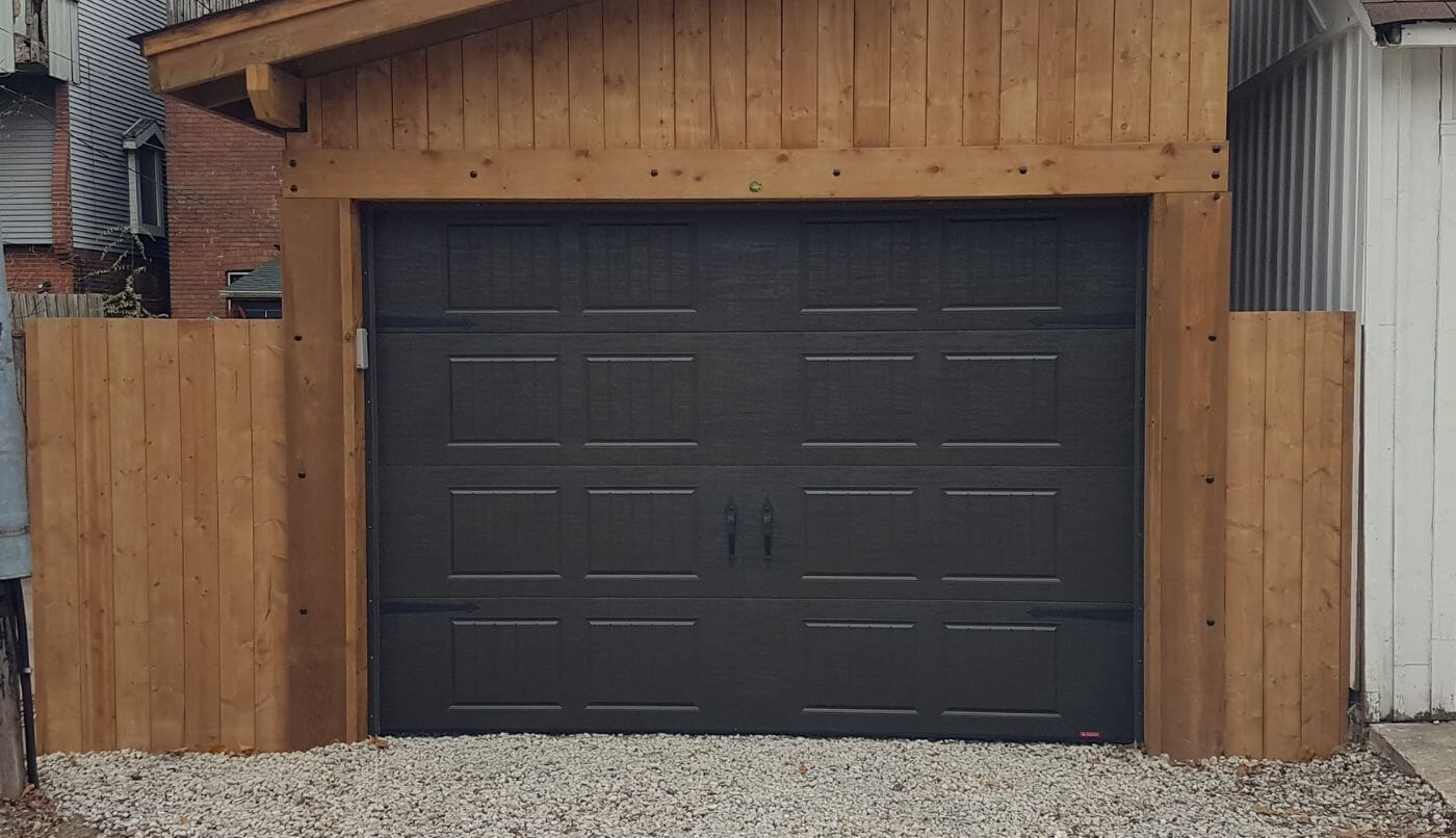 A garage door adjacent to a wooden fence, creating a rustic and cohesive outdoor aesthetic.